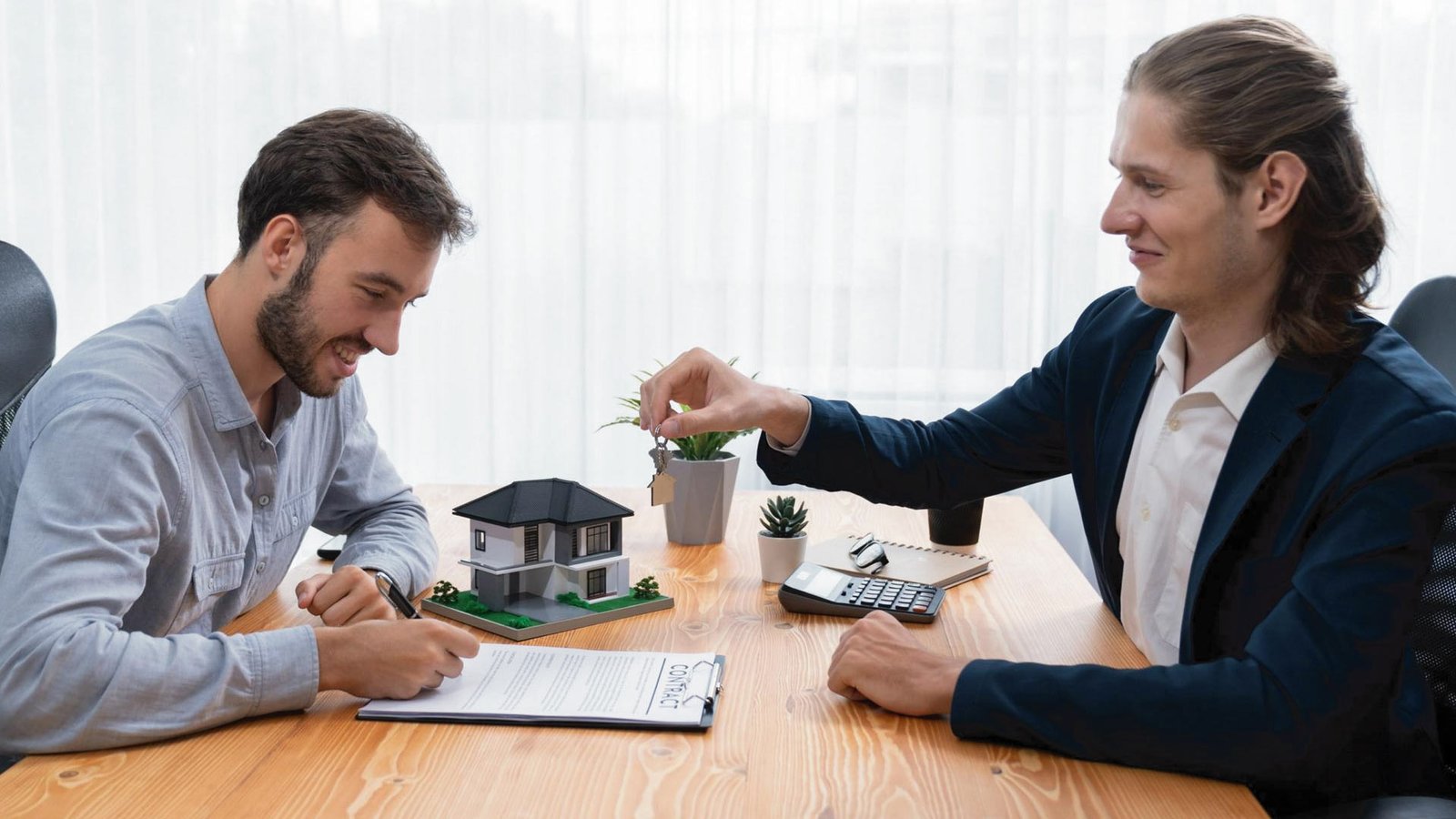 Real estate deal closing with contract, keys, and property model on desk.